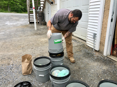 The property manager dumping food scraps from one five-gallon bucket into another to consolidate them in as few buckets as possible. 